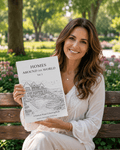 Woman holding a coloring book titled 'Homes Around the World Vol1' in a park.