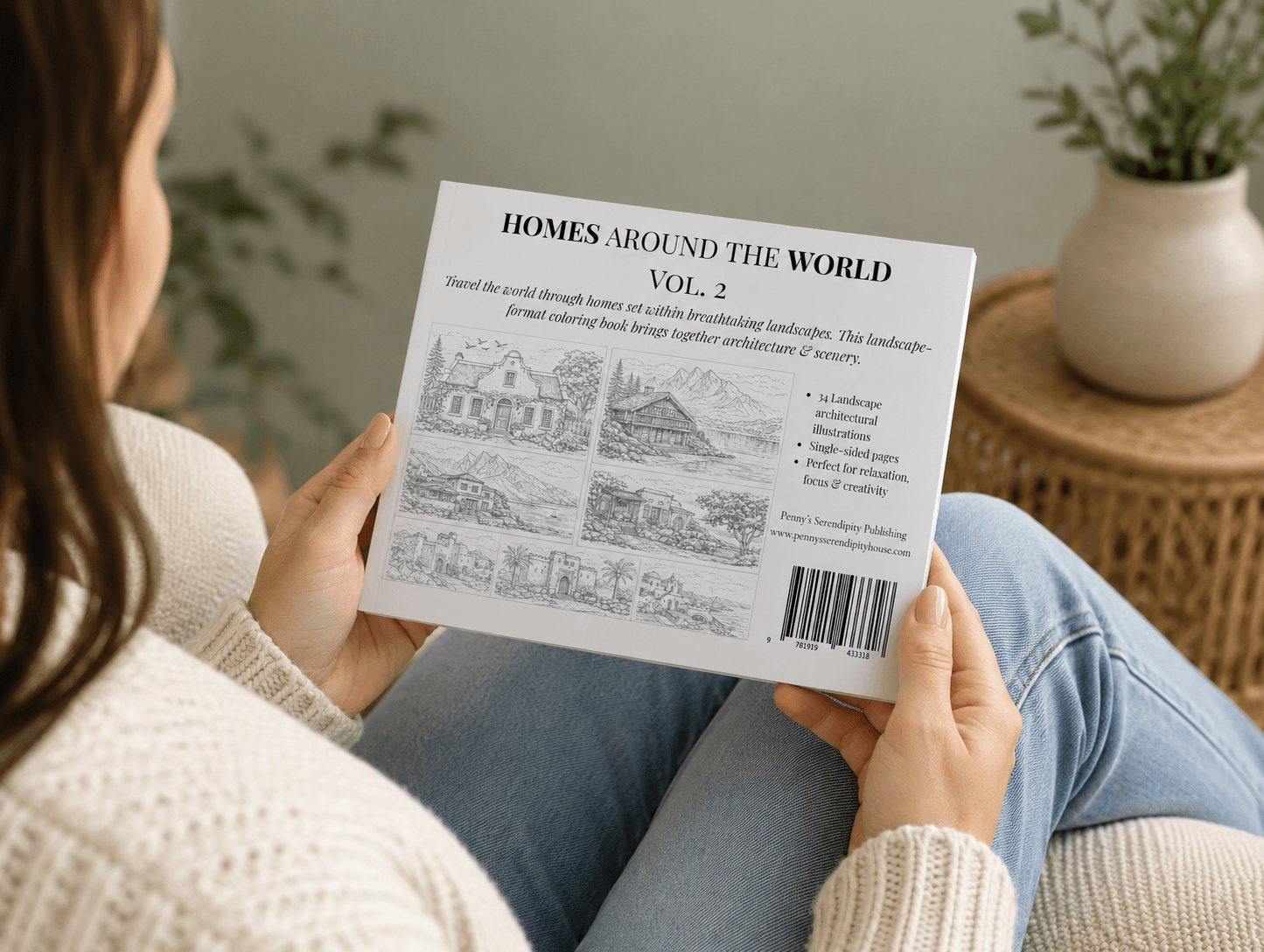 Woman holding a compact coloring  book showing the back cover, titled 'Homes Around the World Vol. 2' in a home setting.